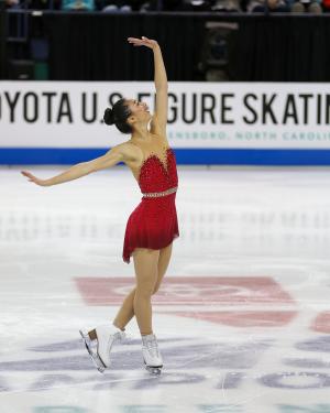 Photo of Sierra Vietta wearing a red figure skating costume completing a skating routine on the ice.