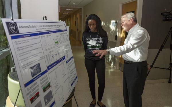Georgia Tech's Executive Vice President for Research Steve Cross takes in one of the research posters at the Project ENGAGES Senior Celebration. (Credit: Sean McNeil, Georgia Tech Research Institute)