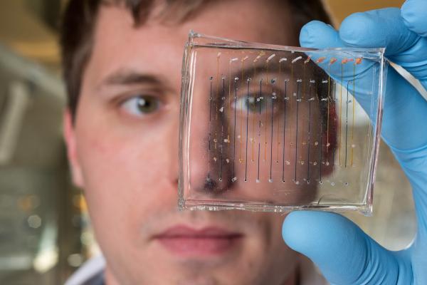 James Dahlman, an assistant professor in the Wallace H. Coulter Department of Biomedical Engineering at Georgia Tech and Emory University, holds a microfluidic chip used to fabricate nanoparticles that could be used to deliver therapeutic genes. (Credit: Rob Felt, Georgia Tech)