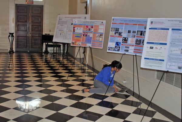 A presenter at the symposium makes last minute preparations among the posters in the halls of the Historic Academy of Medicine at Georgia Tech.