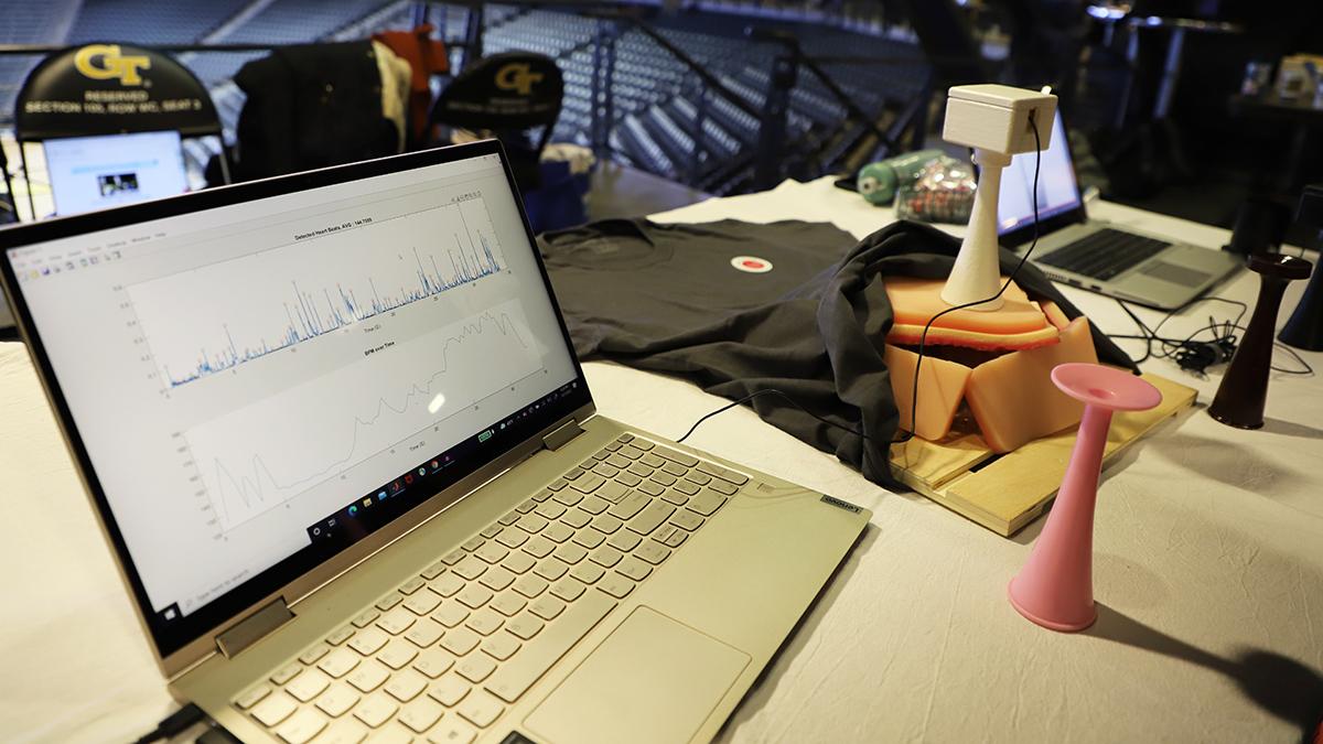 A laptop displays sample fetal heart rate data — detected heart beats in the top chart and heart rate over time on the bottom — alongside the prototype Heartone device at right atop a simulated womb. The team of five biomedical engineering undergraduates developed the device as part of the Coulter BME Global Health Capstone program and showcased their results at Georgia Tech's Fall 2021 Capstone Design Expo. (Photo: Joshua Stewart)