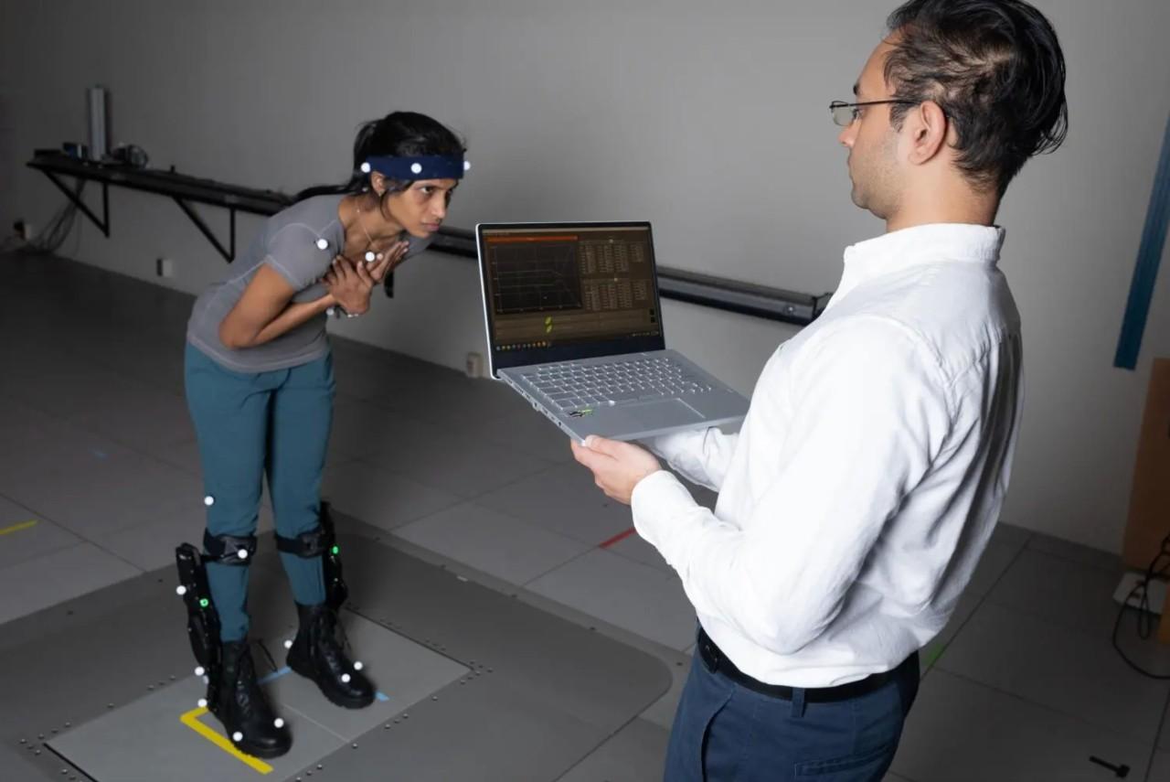 On the left side of the photo is postdoctoral fellow Surabhi Simha demonstrating robotic ankle exoskeleton boots while research engineer Rish Rastogi, right, monitors some of the data being collected on a laptop.