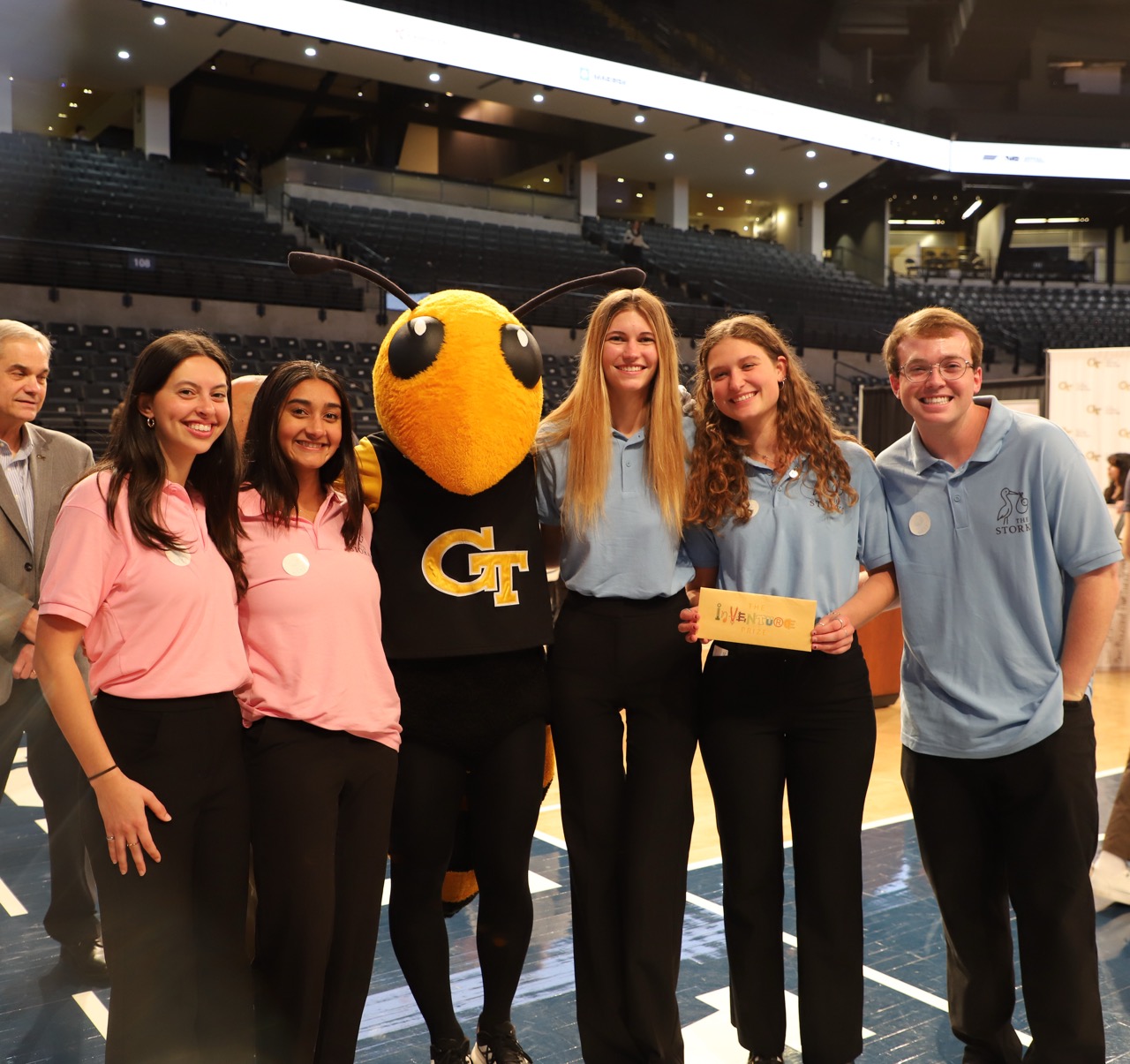 A photo of a team of students holding an envelope with a golden ticket inside from the Inventure Prize program as the Georgia Tech Buzz mascot stands among them.