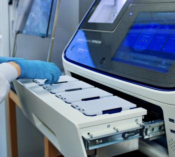 A hand with a blue glove placing a pipette tip tray into the Sanger Sequencing Machine