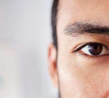 close up of man's brown eye. His dark eyebrows, dark hair, and ear are visible
