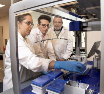 From left, Lorena Chaves, Jose Assumpcao, and Philip Santangelo are standing in a lab examining mRNA samples.