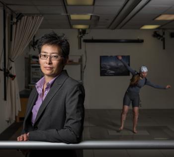 Photo of Professor Lena Ting in the foreground with a research subject in the background 