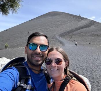 Photo of couple Tushar (on the left) and his wife Mattie (on the right) standing in front of a sand dune