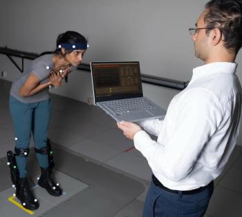 Photo of BME professor and researcher with a student demonstrating an exoskeleton human balance study