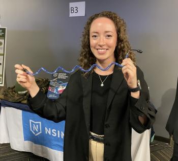 Photo of a female BME student holding a medical device prototype her team created for the College of Engineering Capstone Expo