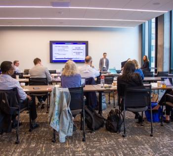 Photo of a research team conducting a presentation about their product while a group of attendees watch