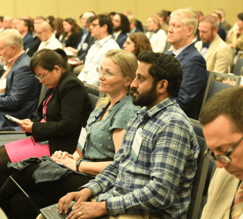 Audience members seated in a large conference room, listening attentively during a professional biomedical engineering meeting.