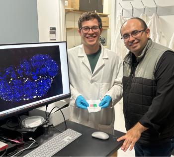Photo of Dr. Ahmet Coskun and his lab research student hold the "diet-on-a-chip" device.
