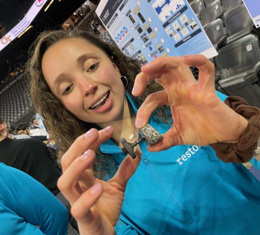 Photo of a female BME student wearing a bright blue shirt holding a device her team created as part of their senior capstone project