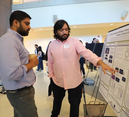 Photo of two male students viewing a research poster at the AI Symposium poster presentation.