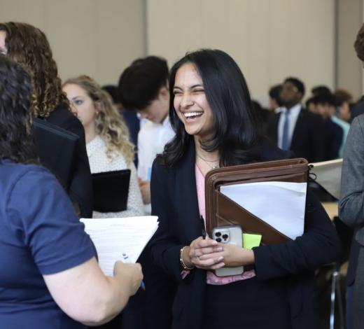 Female student with a binder in her hand talking to an employer