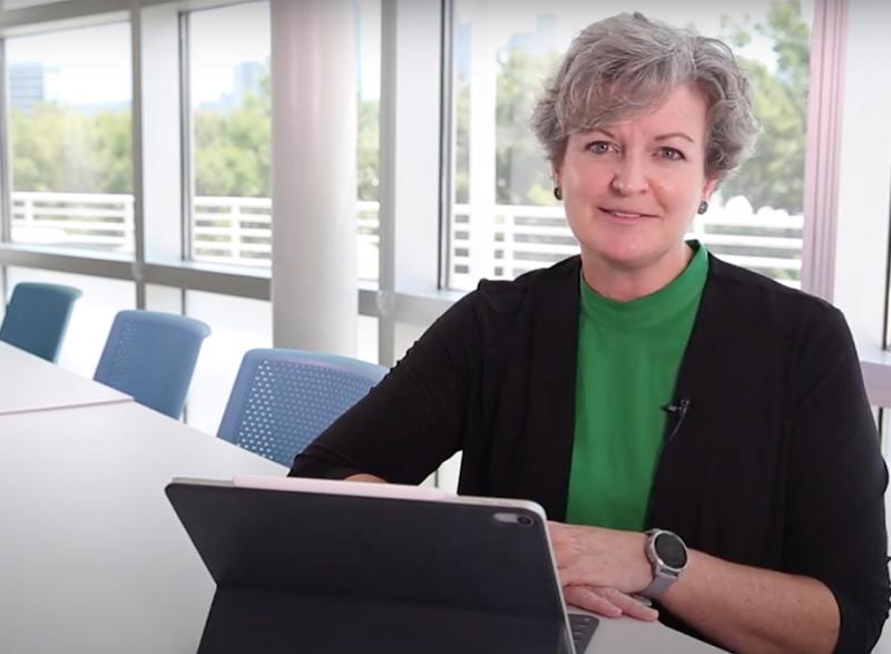 Cristi Bell-Huff sits at a conference table with her tablet computer.