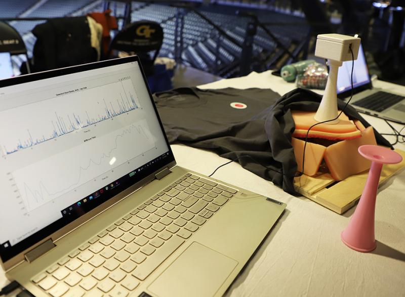 A laptop displays sample fetal heart rate data — detected heart beats in the top chart and heart rate over time on the bottom — alongside the prototype Heartone device at right atop a simulated womb. The team of five biomedical engineering undergraduates developed the device as part of the Coulter BME Global Health Capstone program and showcased their results at Georgia Tech's Fall 2021 Capstone Design Expo. (Photo: Joshua Stewart)