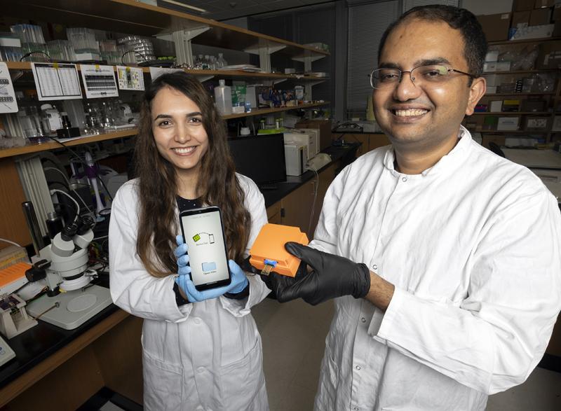 Postdoctoral fellow Neda Rafat and Assistant Professor Aniruddh Sarkar with the Bluetooth reader and smartphone app their team developed to display test results from a new electronic Covid-19 test chip. (Photo: Candler Hobbs)