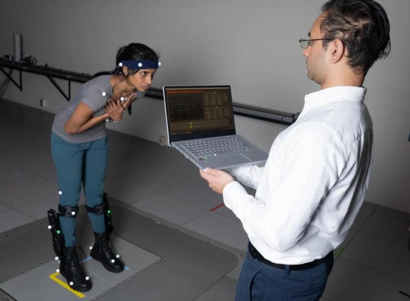On the left side of the photo is postdoctoral fellow Surabhi Simha demonstrating robotic ankle exoskeleton boots while research engineer Rish Rastogi, right, monitors some of the data being collected on a laptop.