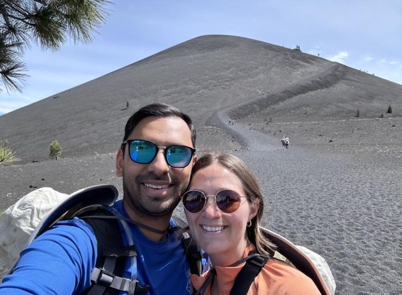 Photo of couple Tushar (on the left) and his wife Mattie (on the right) standing in front of a sand dune