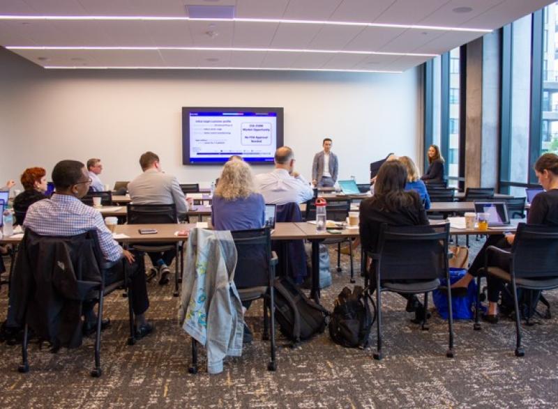 Photo of a research team conducting a presentation about their product while a group of attendees watch