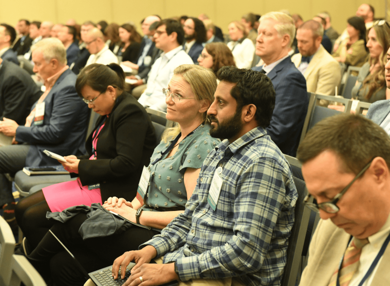 Audience members seated in a large conference room, listening attentively during a professional biomedical engineering meeting.