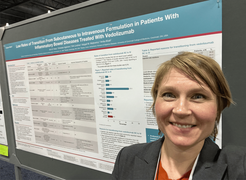 Conference attendee standing in front of a scientific research poster at a professional meeting.