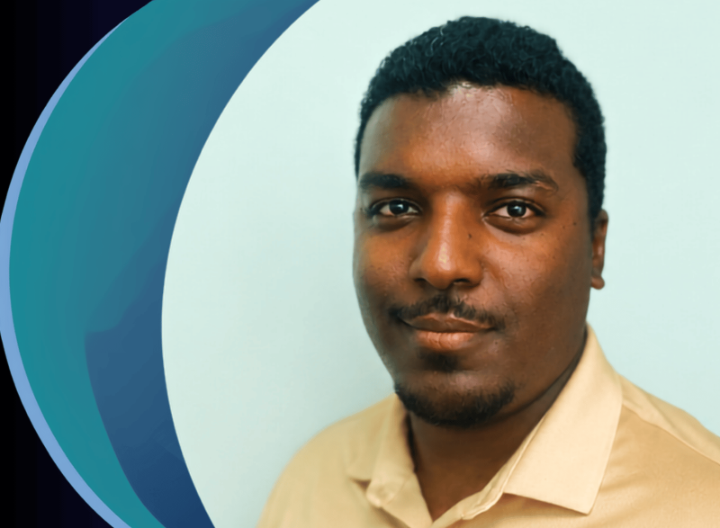 Head-and-shoulders portrait of a person wearing a light-colored collared shirt against a light background. A large blue and teal circular graphic element appears behind the person along the left side of the image. The person faces the camera.