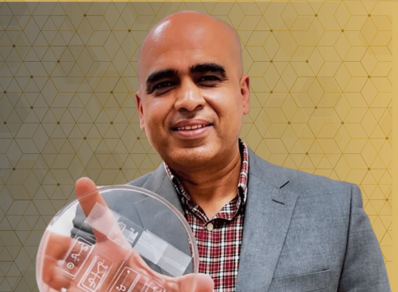A person holding a clear laboratory petri dish against a gold geometric background with a biomedical research theme.
