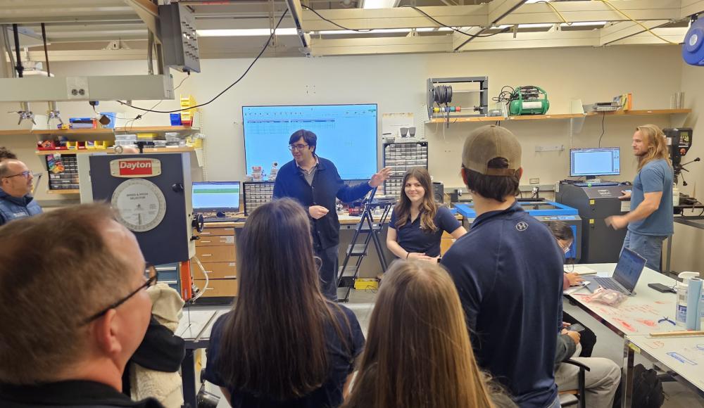 Photo of a group of prospective students and parents taking a tour of the BME Design Shop. Man speaking to the group (he is the manager of the makerspace).