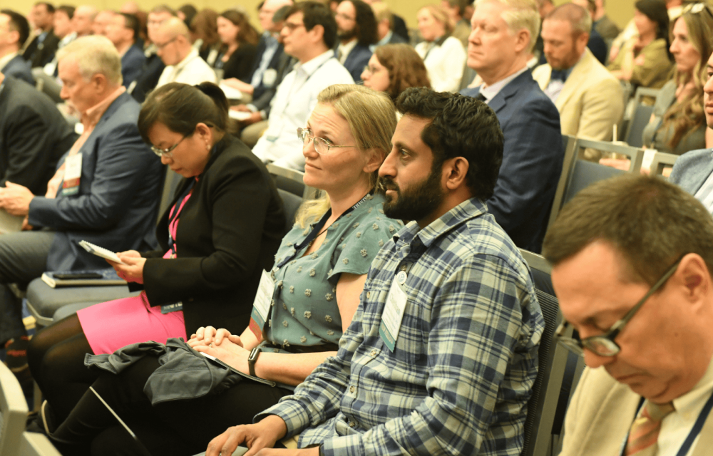 Audience members seated in a large conference room, listening attentively during a professional biomedical engineering meeting.