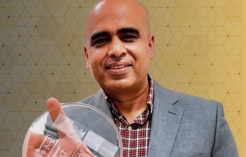A person holding a clear laboratory petri dish against a gold geometric background with a biomedical research theme.
