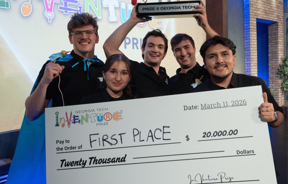 Five members of the winning Georgia Tech InVenture Prize team pose onstage holding a large ceremonial check for $20,000 and a trophy labeled “Prize @ Georgia Tech.” The oversized check reads “First Place” and “Winning 1st Place,” with the Georgia Tech InVenture Prize logo displayed prominently in the foreground. Colorful InVenture Prize signage appears in the background.