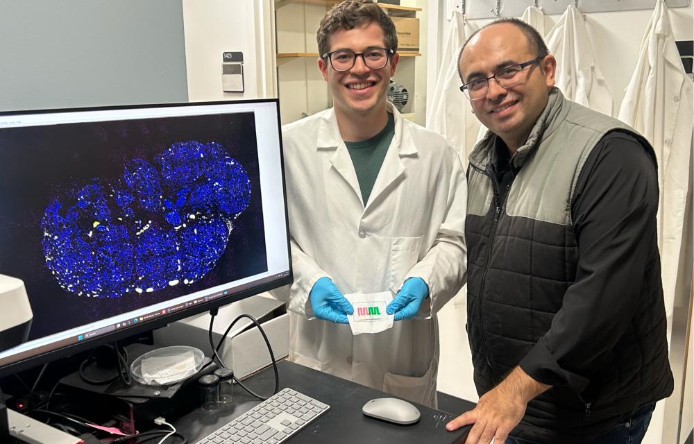 Photo of Dr. Ahmet Coskun and his lab research student hold the "diet-on-a-chip" device.